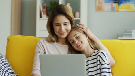 Linda-Adolescente-Apoyada-En-El-Hombro-De-Su-Madre-Mientras-Ve-Algo-En-La-Laptop-En-La-Sala-De-Estar