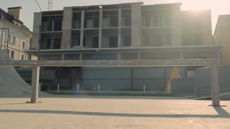 skateboarder girl skating in a skatepark in front of a house under construction