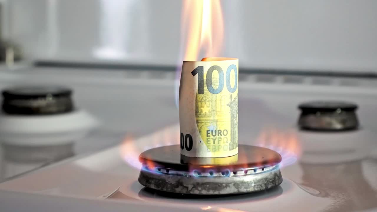 Concept of gas crisis. 100 euro bill is burning on a kitchen stove burner. European cash money. High prices of natural resources. Fire flame. Utility debt. Energy war. Saving home budget.