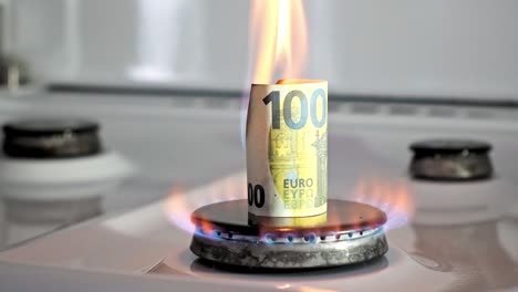 concept of gas crisis. 100 euro bill is burning on a kitchen stove burner. european cash money. high prices of natural resources. fire flame. utility debt. energy war. saving home budget.