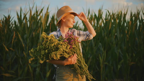 woman farmer holding flowers in a cornfield at sunset