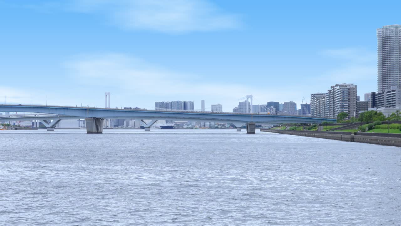 A wide, peaceful shot of the expansive Tokyo Bay with the modern Harumi Bridge and the distant skyline