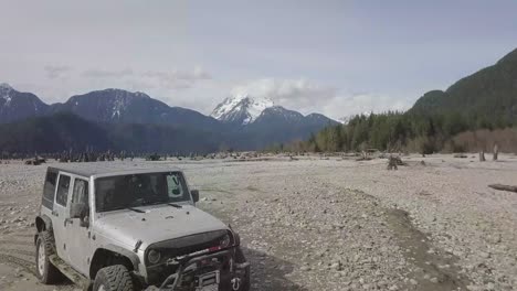 drone aerial shot of two jeeps by the water desert in no man's land in british columbia