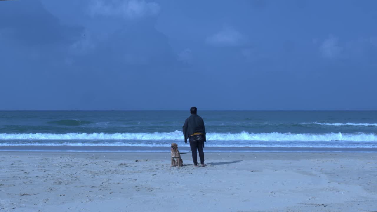 강아지 와 함께 해변 에 앉아 있는 남자 가 서서 시각화 하고 있다