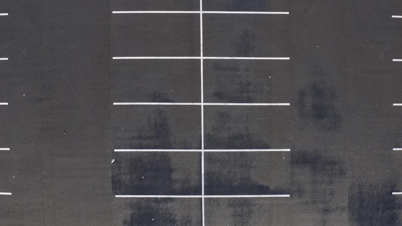 공중은 어두운 포장 주차장에 그려진 흰색 선 디자인으로 내려갑니다.