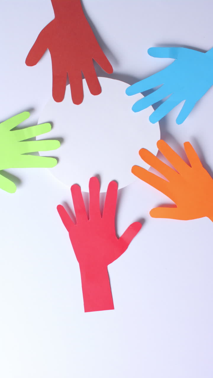Vertical video of hands touching circle made of colourful paper on white background with copy space