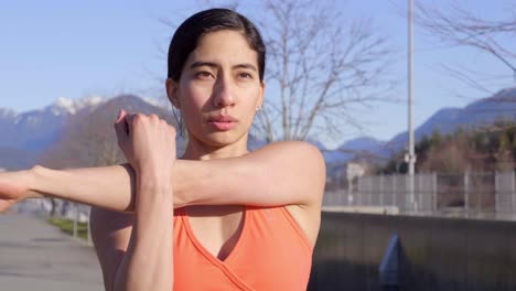 joven atractiva mujer atlética estirando los brazos antes de hacer ejercicio al aire libre