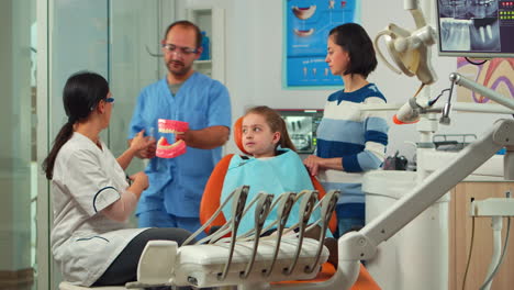 Stomatologist-holding-plaster-model-of-the-mandible-speaking-with-girl-patient.