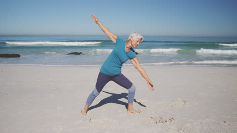 Mujer-Caucásica-Mayor-Practicando-Yoga-En-La-Playa