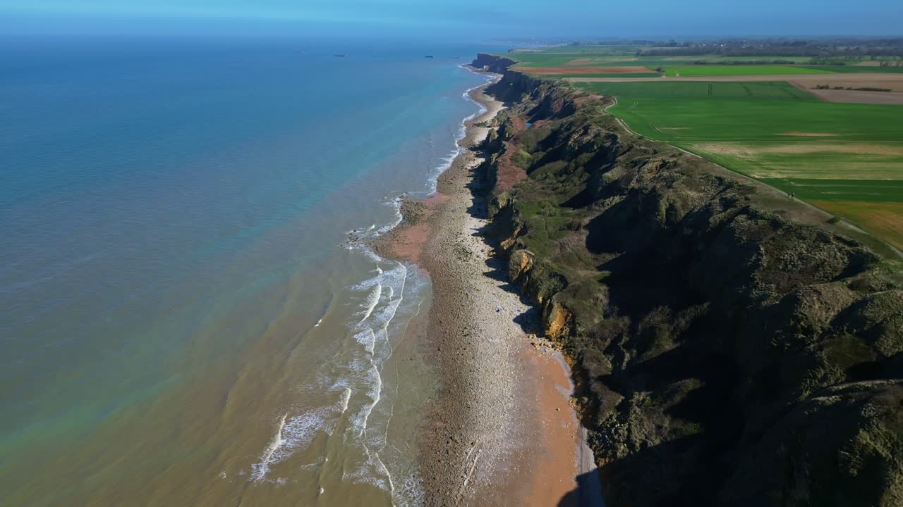 Coastal cliffs and sea at Longues-sur-Mer, Normandy, France. Aerial drone backward ascending