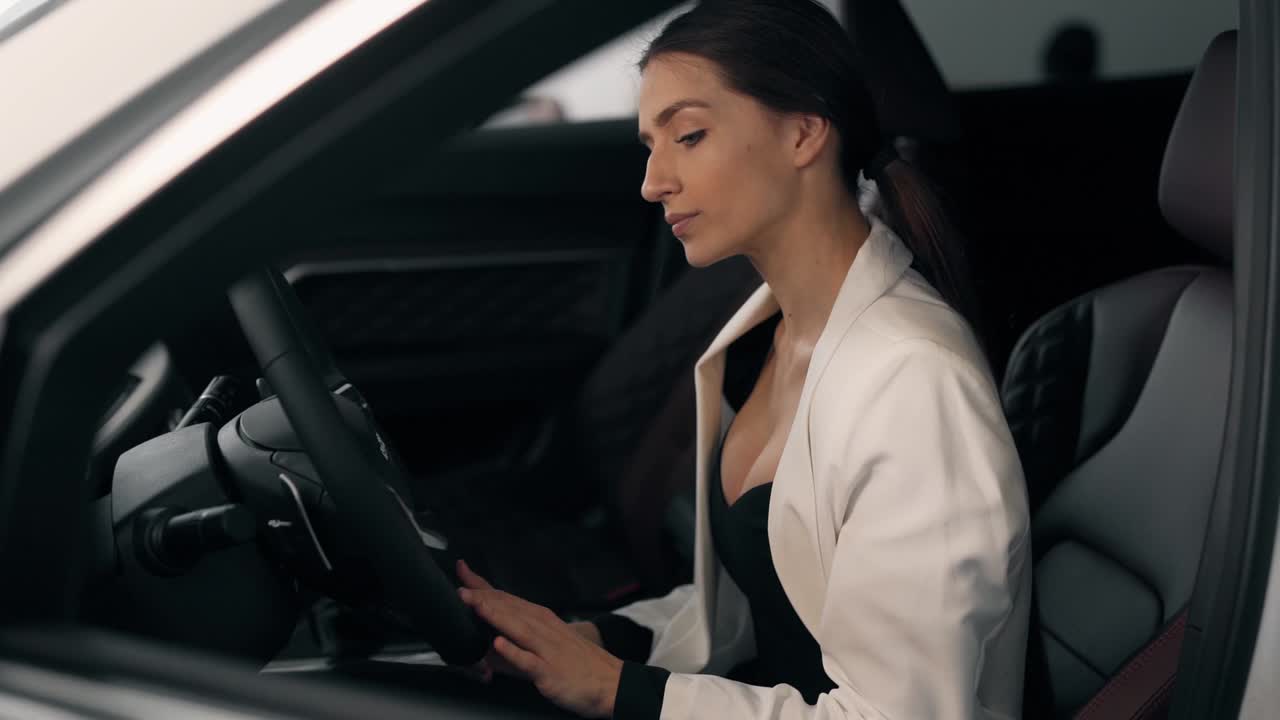 Elegante donna d'affari che guida un'auto in posa davanti alla telecamera.