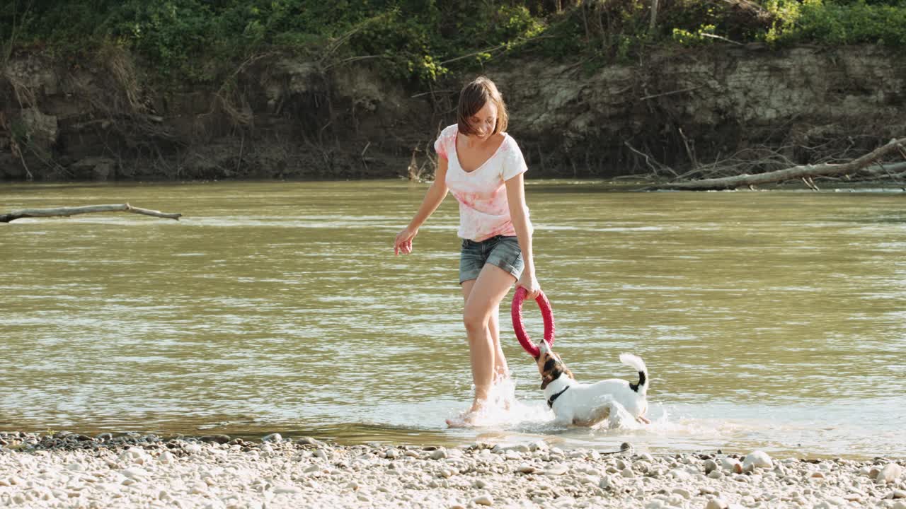Donna che gioca con il cane vicino al fiume