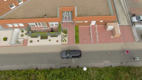 disparo de drone de arriba hacia abajo de personas dejando un coche y entrando en una casa
