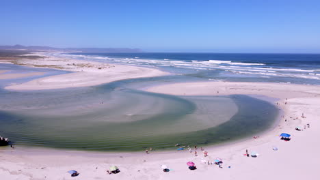 Aerial-of-clear-water-of-estuary-flowing-through-beach-and-breaching-into-ocean