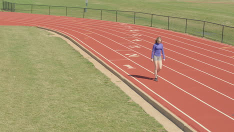 teen girl athlete on a school track outside does forward and reverse lunges in her warm up routine