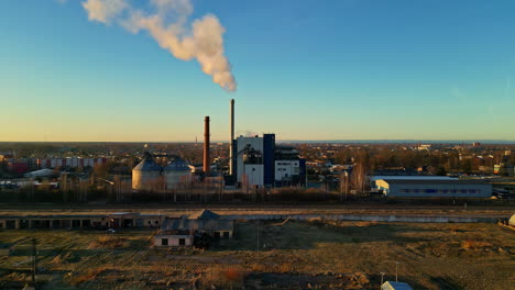 Drone-shot-of-industrial-zone-with-thick-smog-and-burning-fossil-fuels-at-sunset