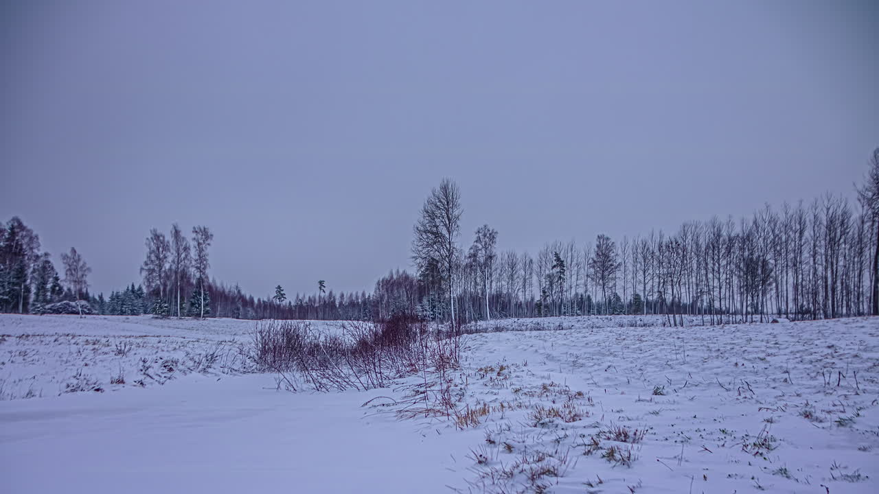 Ripresa dal basso di un campo innevato con movimento di nuvole dopo il tramonto in timelapse lungo la campagna rurale durante la sera