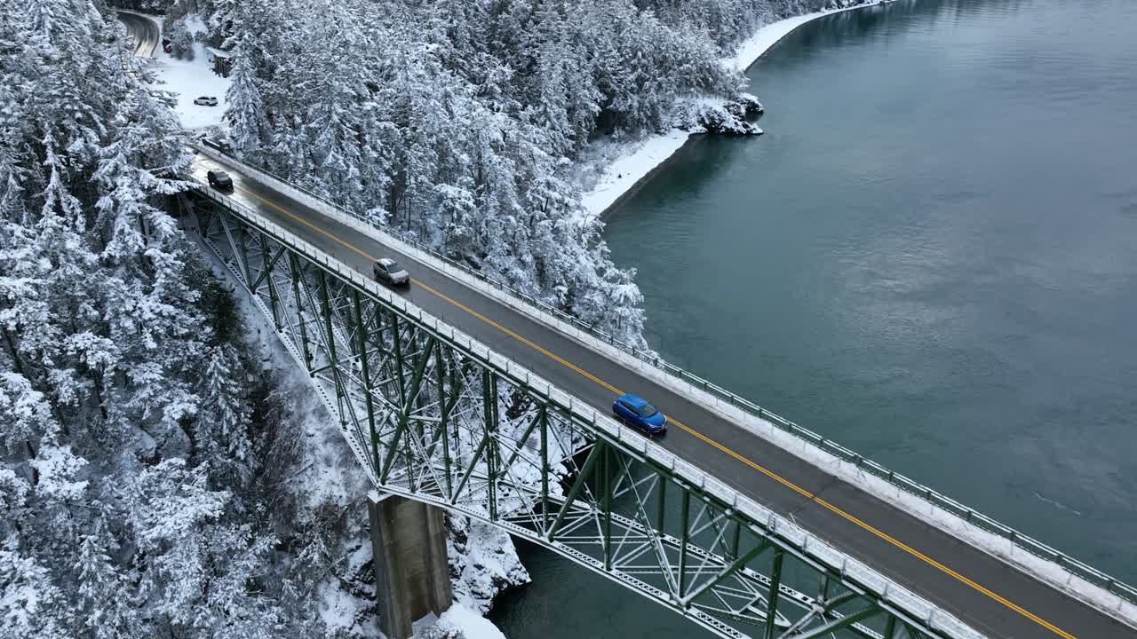 물 위 높은 다리를 건너기 위해 눈 덮인 본토를 떠나는 자동차들의 공중 전망