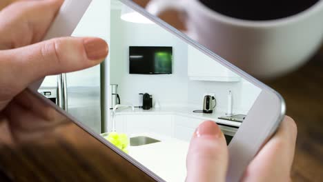 person holding smartphone with modern kitchen interiors displayed on screen