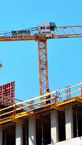 workers on skyscraper site. workers are actively constructing a high-rise building using a crane and scaffolding under clear blue skies