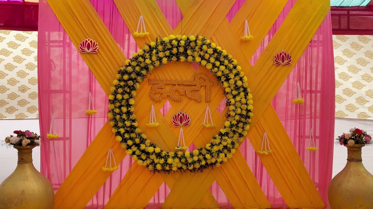 Beautiful Haldi stage decoration with yellow floral wreath, pink drapery and traditional Indian motifs. Ideal for wedding, pre-wedding celebrations, cultural events and festive occasions.