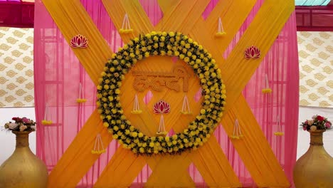 beautiful haldi stage decoration with yellow floral wreath, pink drapery and traditional indian motifs. ideal for wedding, pre-wedding celebrations, cultural events and festive occasions.