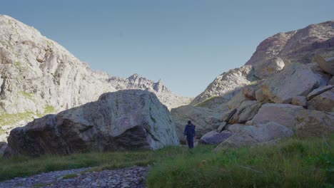 a man trekking alone between the rocks, walking towards the camera