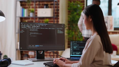 asian woman is seen typing code for an app development project on her computer