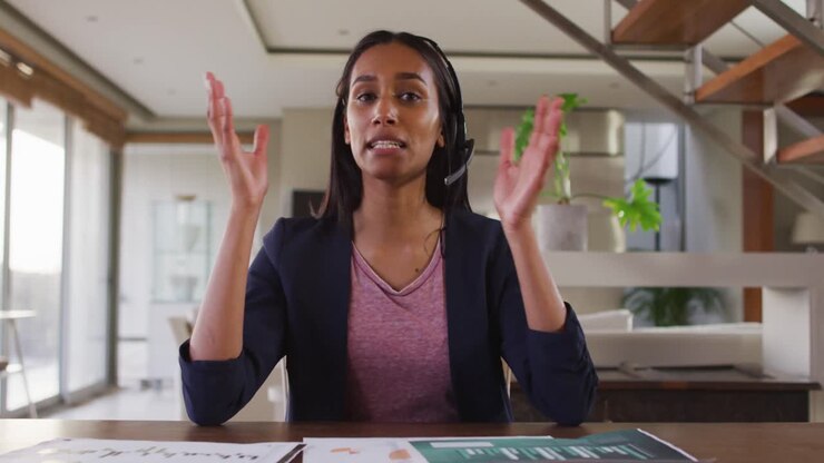 Mixed race woman by desk at home using laptop having video chat