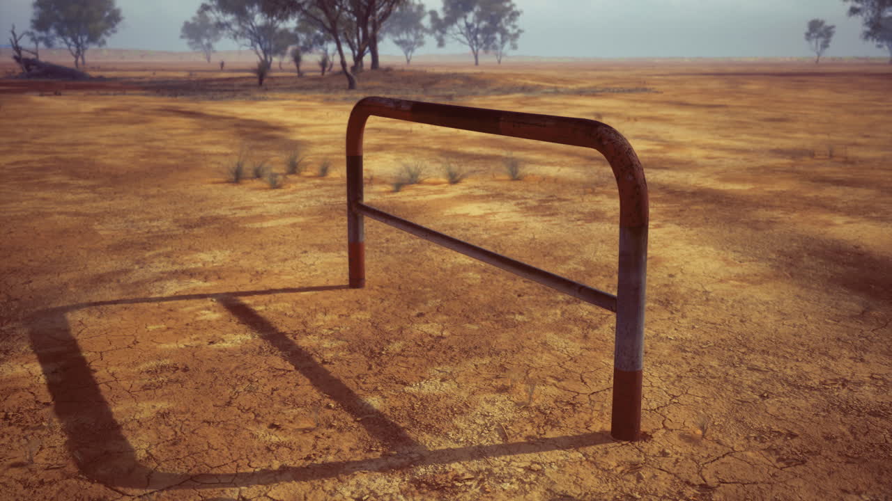 Metal structure on dry cracked earth in a barren landscape during sunny weather