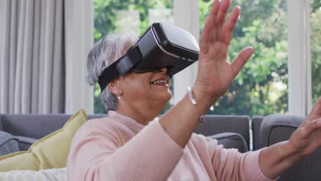 Glückliche-Seniorin-Mit-Gemischter-Abstammung,-Die-Ein-VR-Headset-Trägt-Und-Zu-Hause-Spaß-Hat
