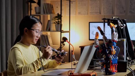 teen asian girl holding and fixing the circuit board while repairing a cyborg hand at home