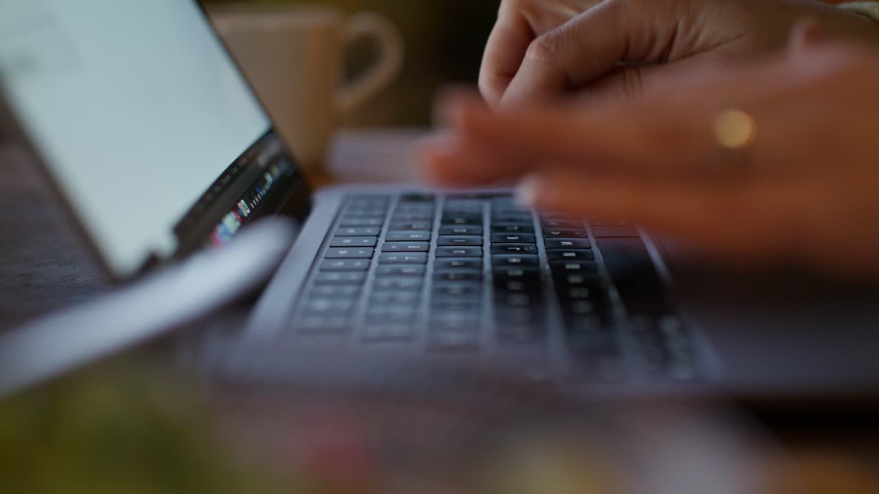 mujer escribiendo en una computadora portátil en un café