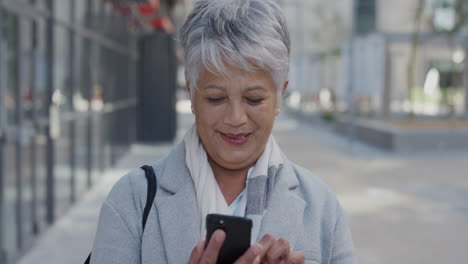 portrait senior indian business woman using smartphone enjoying texting browsing messages on mobile phone reading emails in city slow motion real people series
