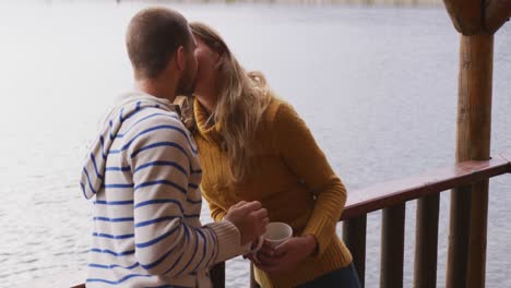 caucasian couple spending time at home together, kissing outside the cabin