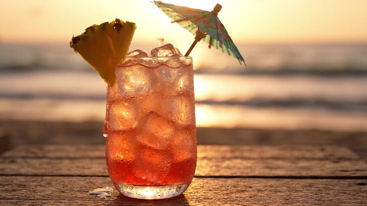 A Refreshing Tropical Cocktail with a Pineapple Slice and Colorful Umbrella Enjoyed by the Beach During Sunset, Perfect for Relaxation and Summer Vibes