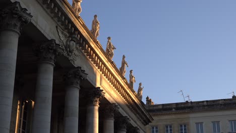 Classical-marble-statues-adorn-the-roof-of-the-Bordeaux-Opera-house-palace-in-France,-Pan-right-looking-up-shot