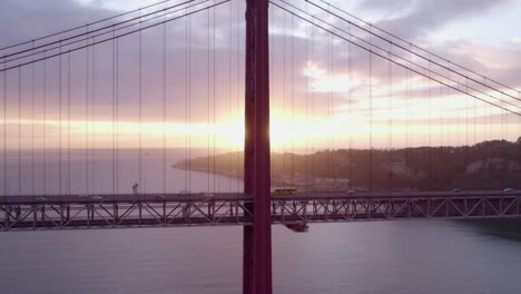 traffic drives on famous ponte 25 de abril lisbon during sunrise, aerial