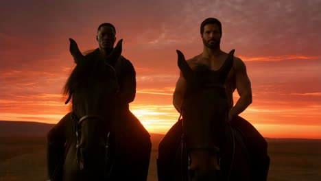 two men on horseback at sunset