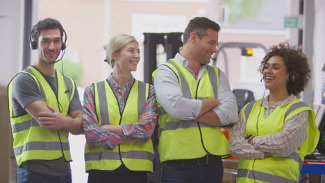 Retrato-De-Un-Equipo-Sonriente-Con-Auriculares-Y-Chalecos-De-Seguridad-De-Alta-Visibilidad-En-Un-Almacén-De-Distribución-Logística