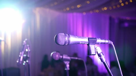 two microphones and musical instruments are set up under a powerful spotlight at a nightclub, all waiting for the party or music show to commence