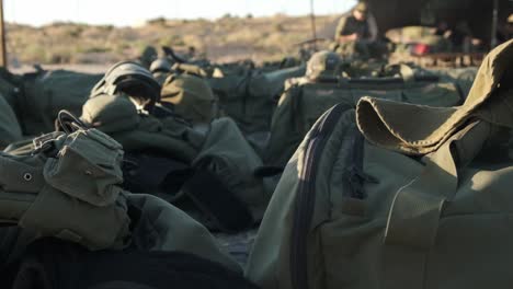 primer plano de bolsas militares y equipo militar en el sol en medio del desierto