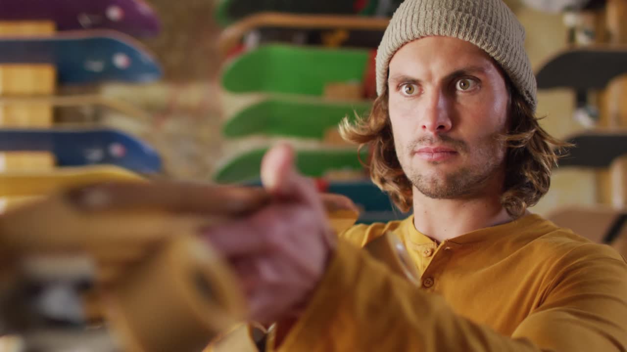 video de un skateboarder caucásico arreglando el skateboard en una tienda de skates