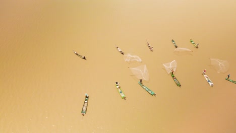 multiple fishermen in bright colorful boars working as a team to catch a shoal of fish