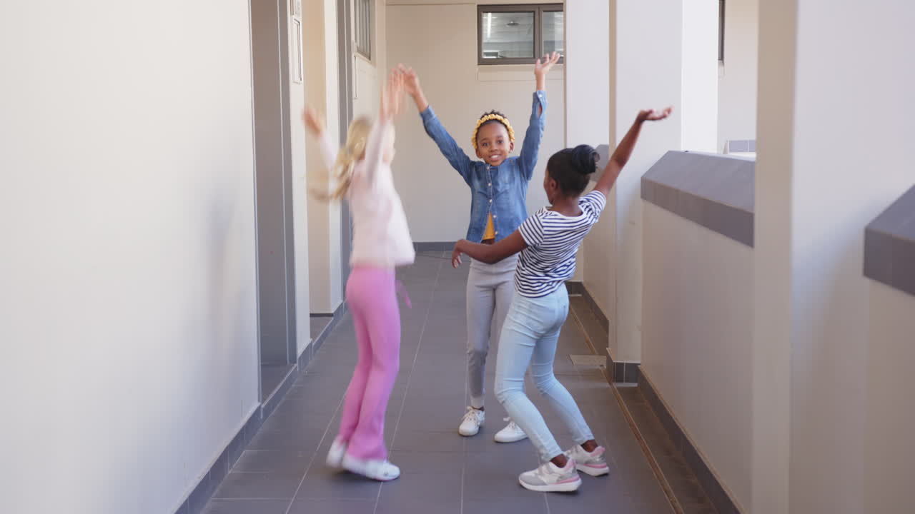 Saltano e giocano, tre ragazze si divertono nel corridoio della scuola.