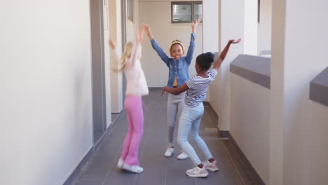 jumping and playing, three girls having fun in school hallway