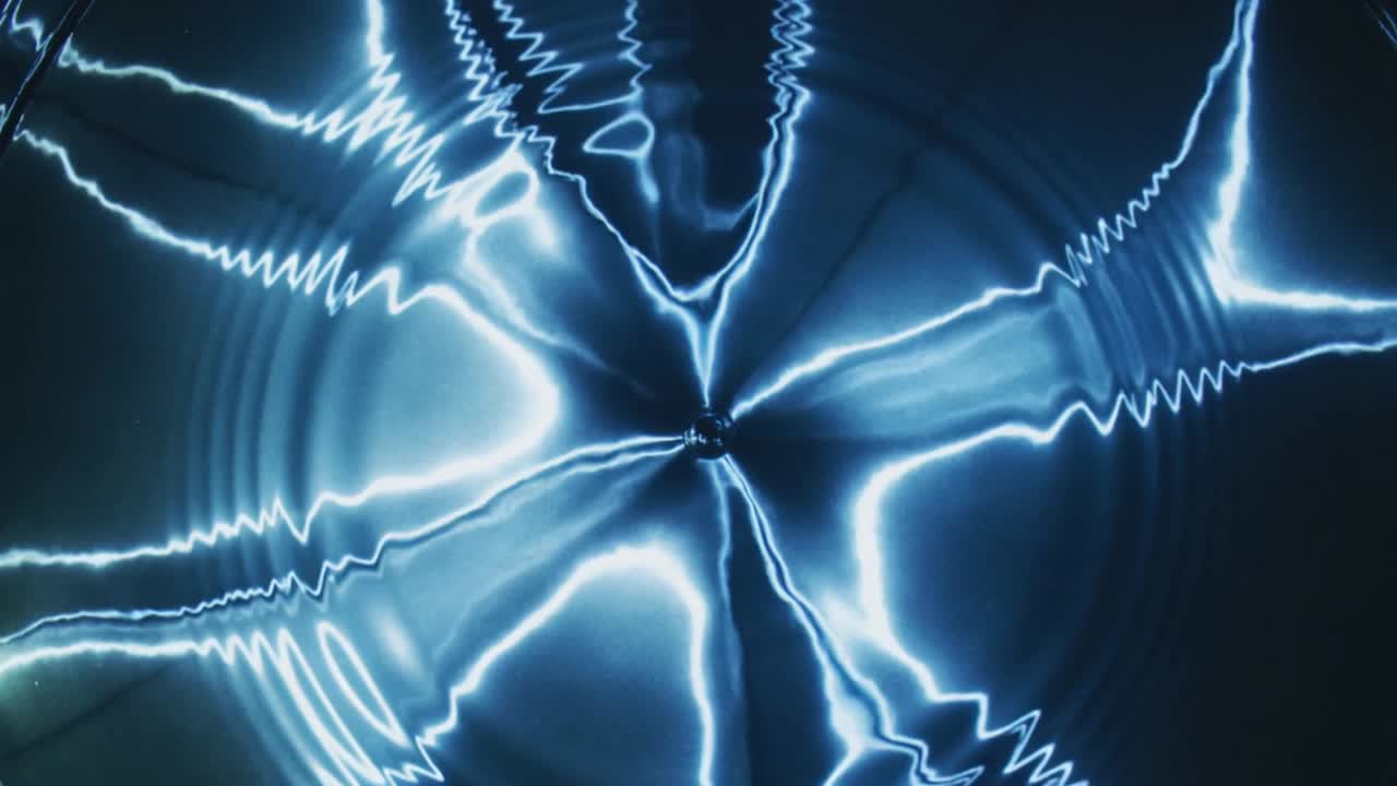 Radiating central bright point sending blue spokes and rings across dark surface, showing waves