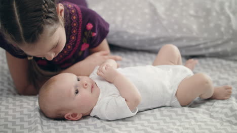 Mädchen-Küsst-Neugeborenes-Baby,-Das-Auf-Dem-Rücken-Liegt.-Schwesterliebe-Konzept