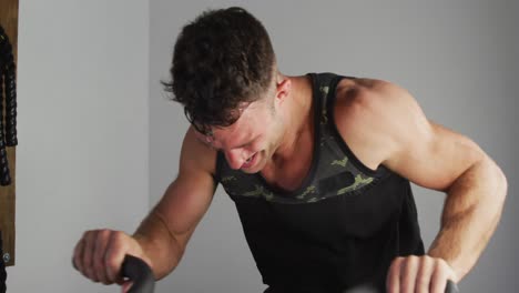 Fit-sweaty-caucasian-man-exercising-on-training-bike-inside-gym