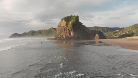 Unglaubliche-Luftdrohnenaufnahme-über-Dem-Schwarzen-Sandstrand-Von-Piha-In-Neuseeland-Bei-Sonnenuntergang